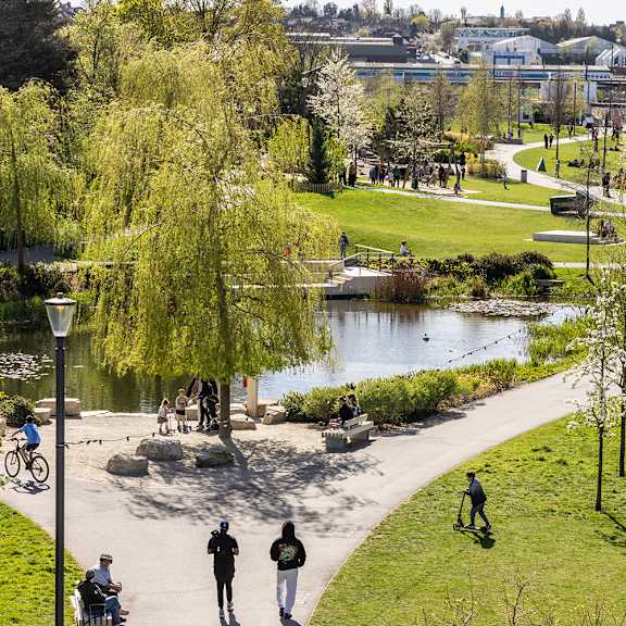 A park with people walking and sitting by a pond.