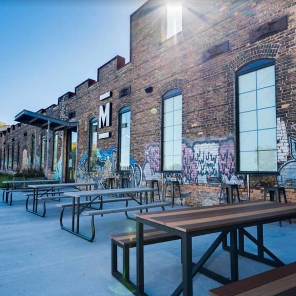 a picnic area with benches and tables in front of a brick building with graffiti on it