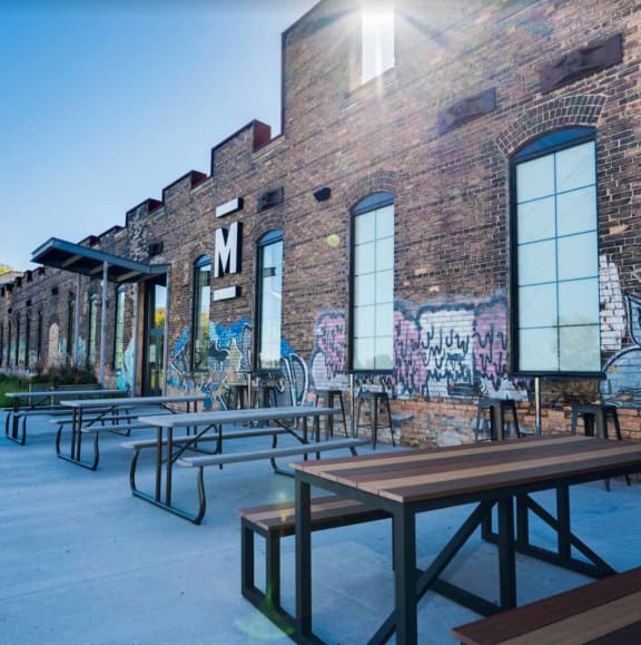 a picnic area with benches and tables in front of a brick building with graffiti on it