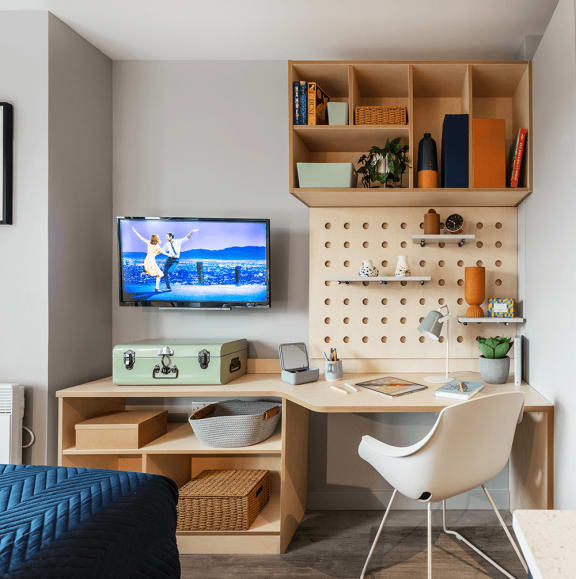 a desk with a monitor and a chair in a bedroom