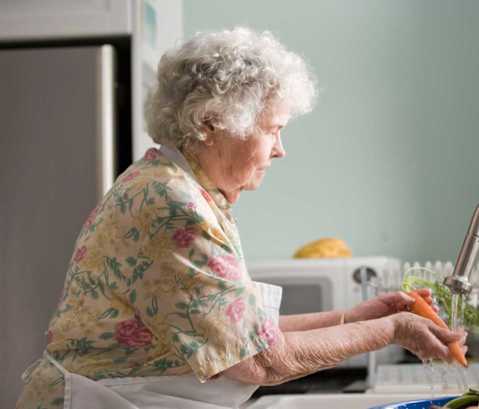 an older woman in a kitchen preparing food