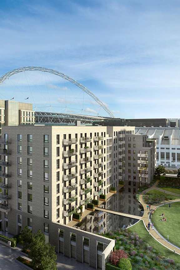 A modern building with a large arched structure in the background at Beton Apartments, Wembley, HA9 0SL