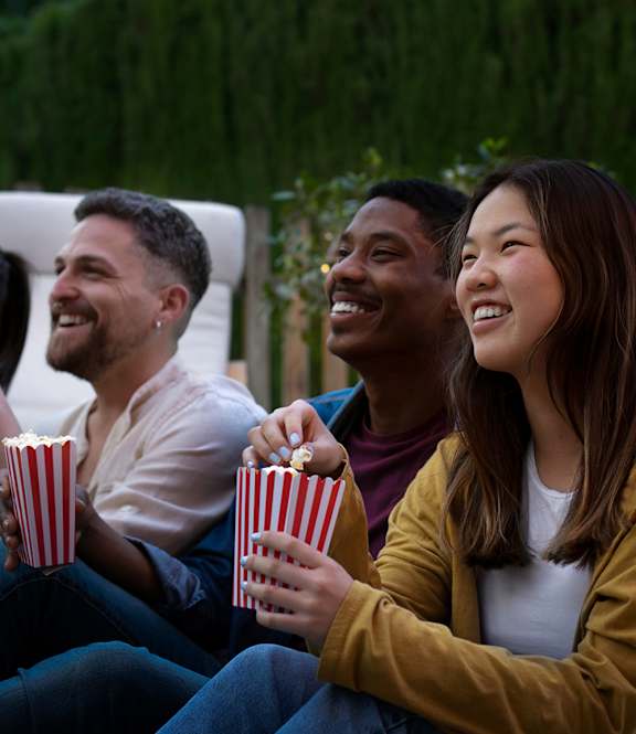 Three people are sitting together and eating popcorn.