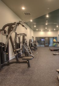 a gym with cardio equipment and weights on the floor