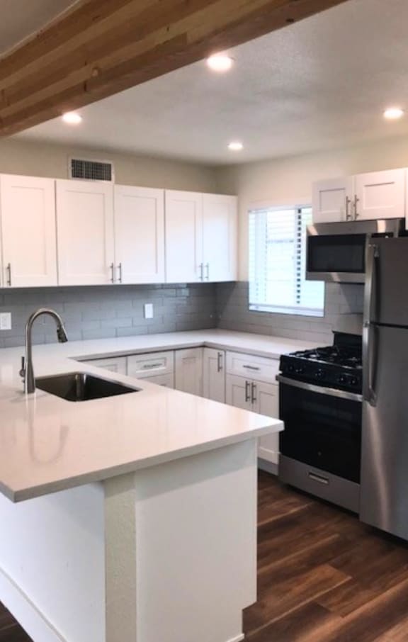 a kitchen with a white counter top and a stainless steel refrigerator