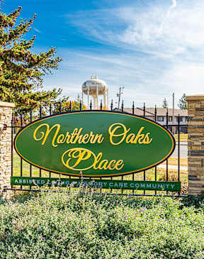 A sign that says "Northern Oaks Place" in front of a water tower.