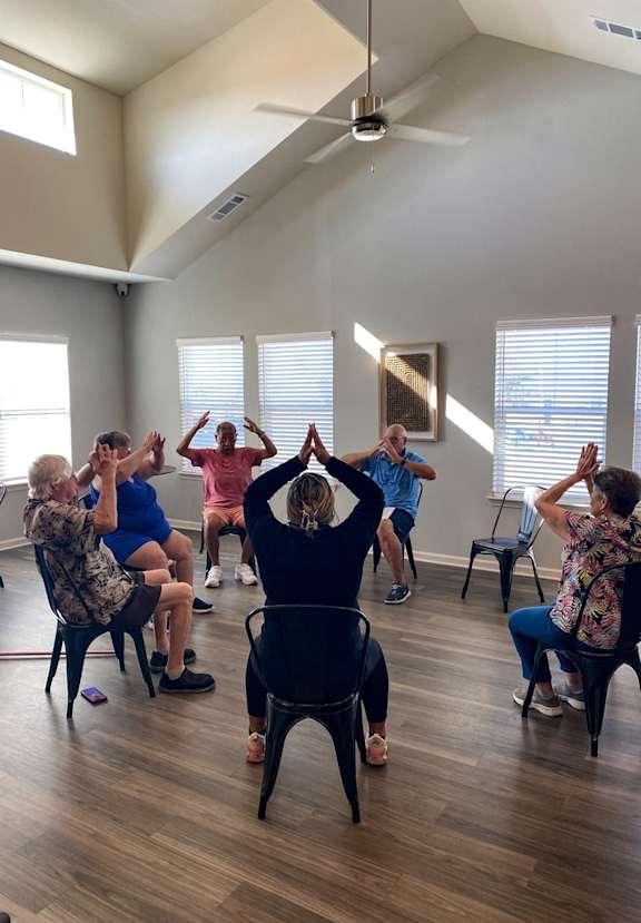 a group of people sitting in chairs in a circle stretching
