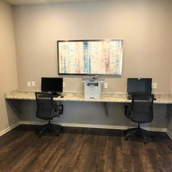 A room with a desk and two chairs with desktop computers
