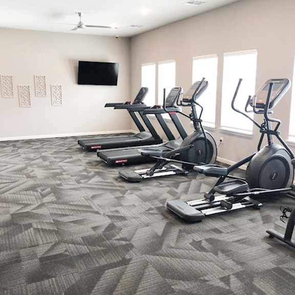 A gym with treadmills and a television on the wall.