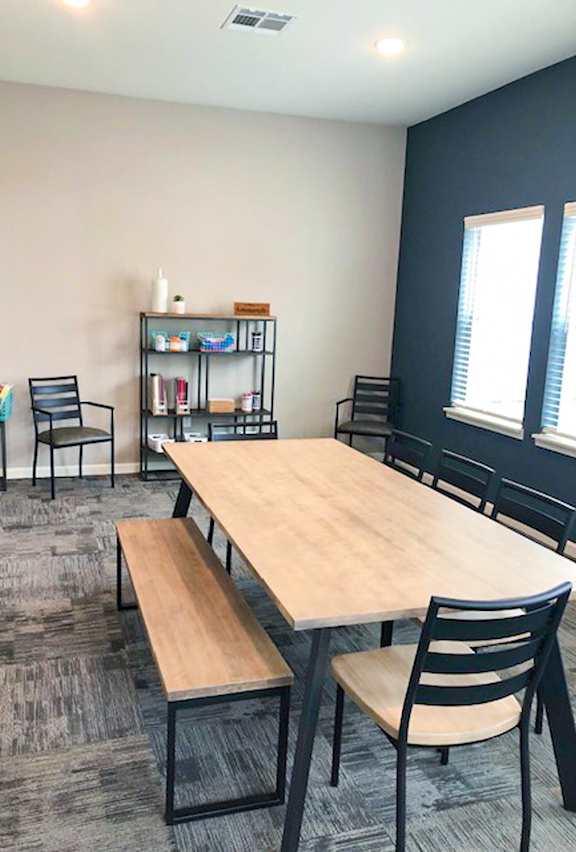 A room with a table, chairs, and a bookshelf.