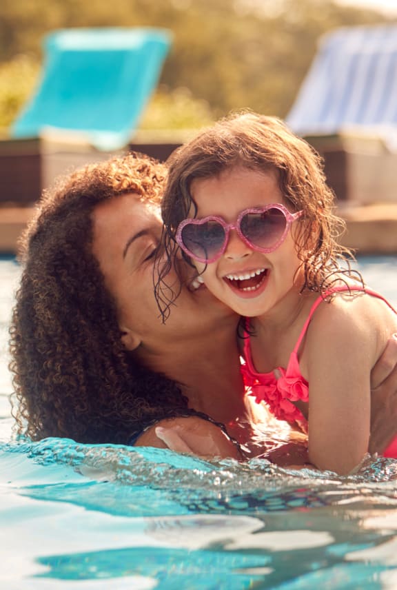 a young girl swimming in a pool with her mother