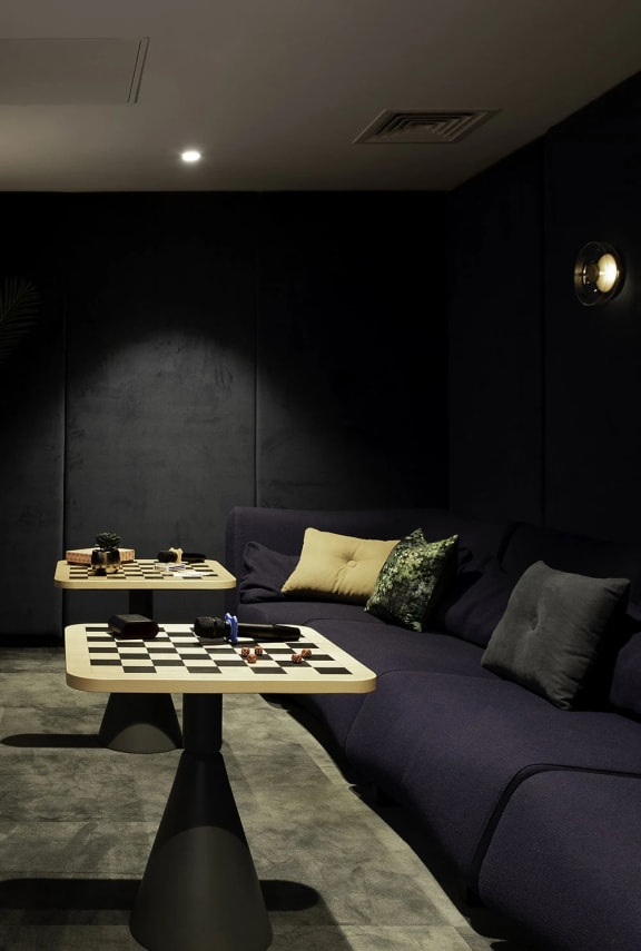a dark living room with a purple couch and two tables with chess and checkers on them