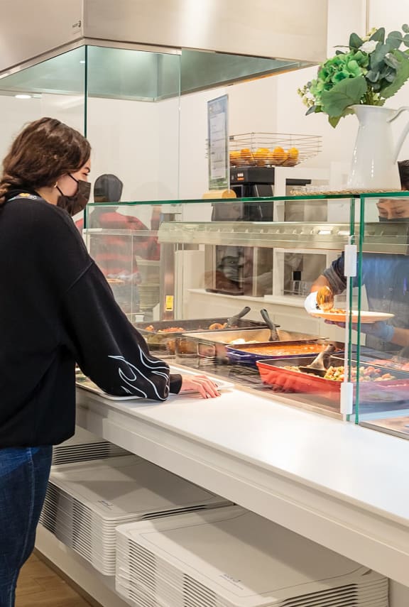 a woman standing in front of a display case of food