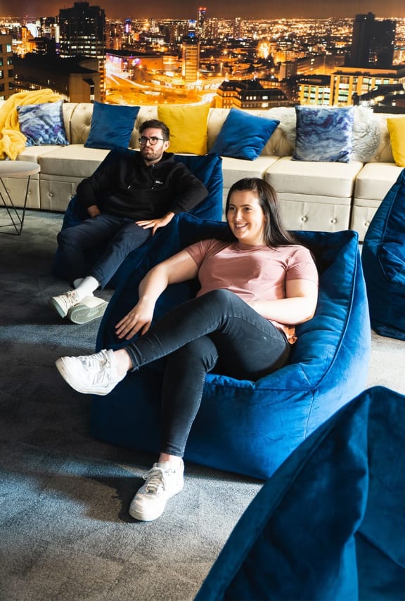 a man and woman sitting on a blue chair in a living room