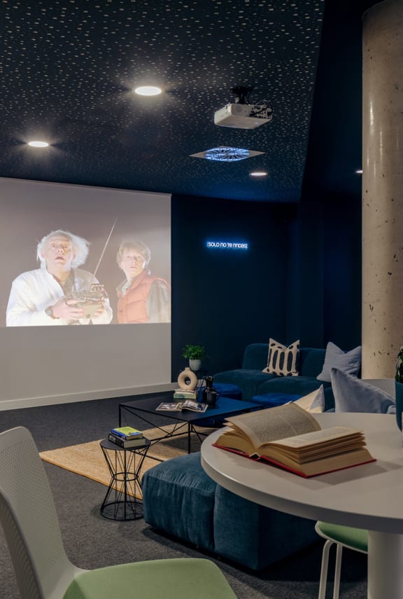 a living room with blue furniture and a projector screen on the wall