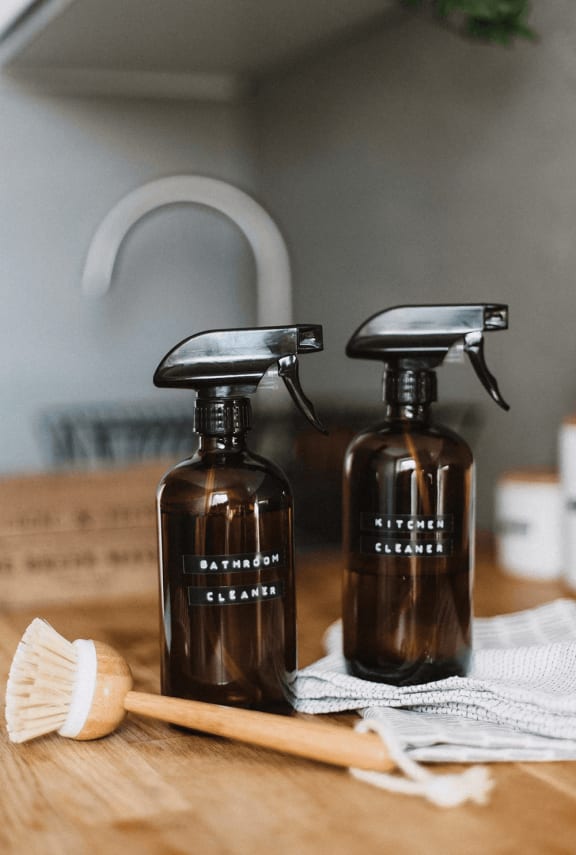 two bottles of liquid soap sitting on a counter with a brush