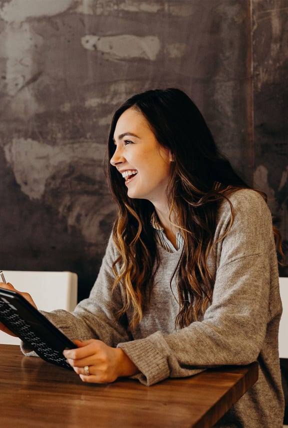 a woman sitting at a table with a laptop computer