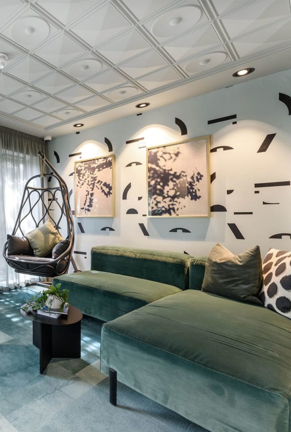 a living room with green couches and a swing chair