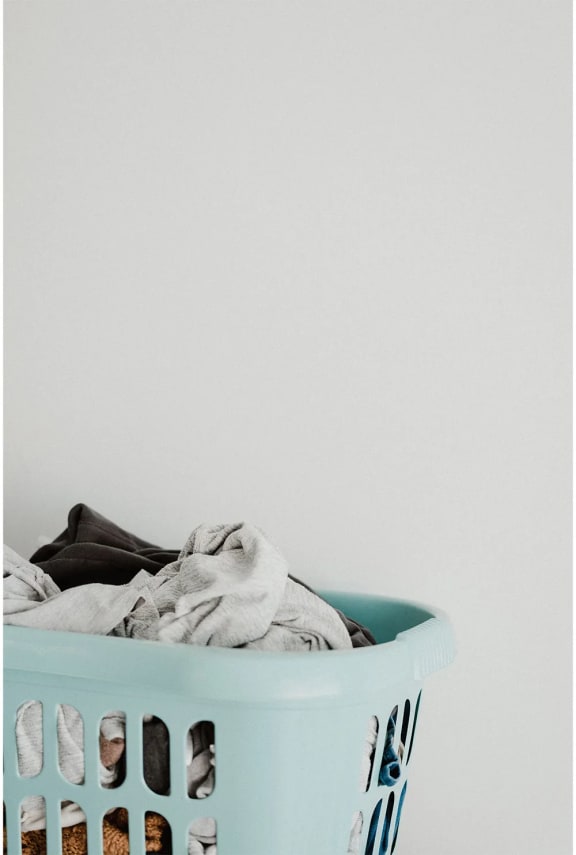 a laundry basket full of clothes in a white room