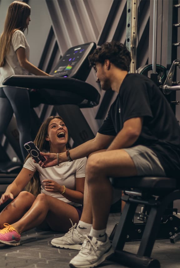 two treadmills and weights in a workout room with a white wall and white