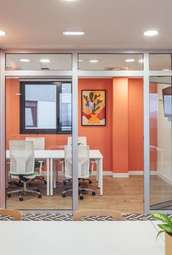 a conference room with orange walls and white tables and chairs