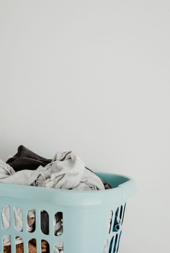 a laundry basket full of clothes against a white wall