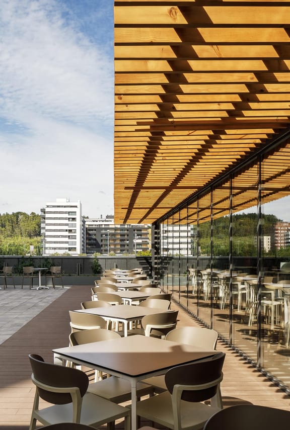 a row of tables and chairs under a wooden canopy on a roof