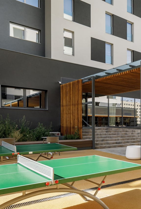 two ping pong tables on a patio with a building in the background