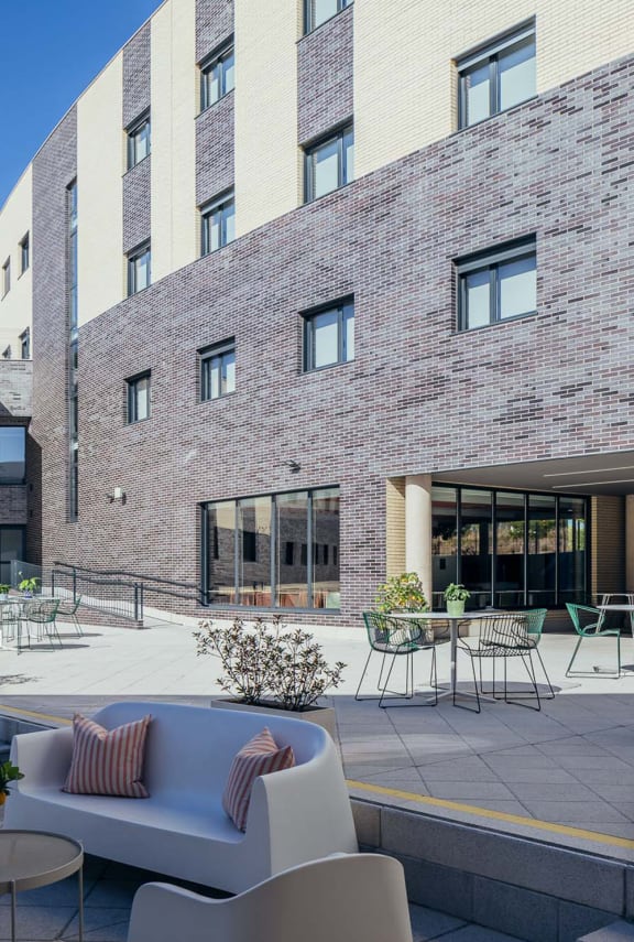a patio with a couch and chairs in front of a brick building