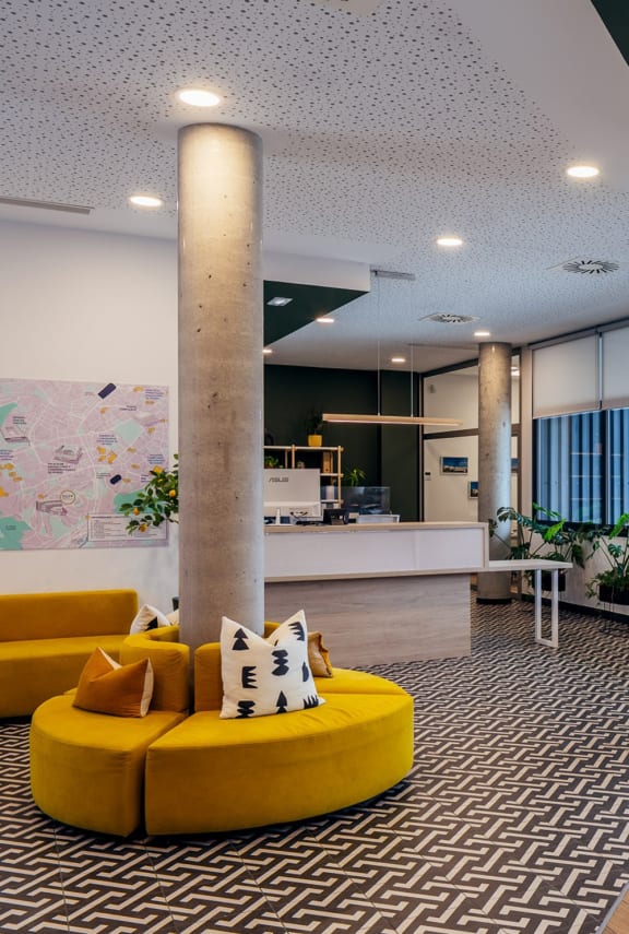 a yellow couch in a lobby with a pillar
