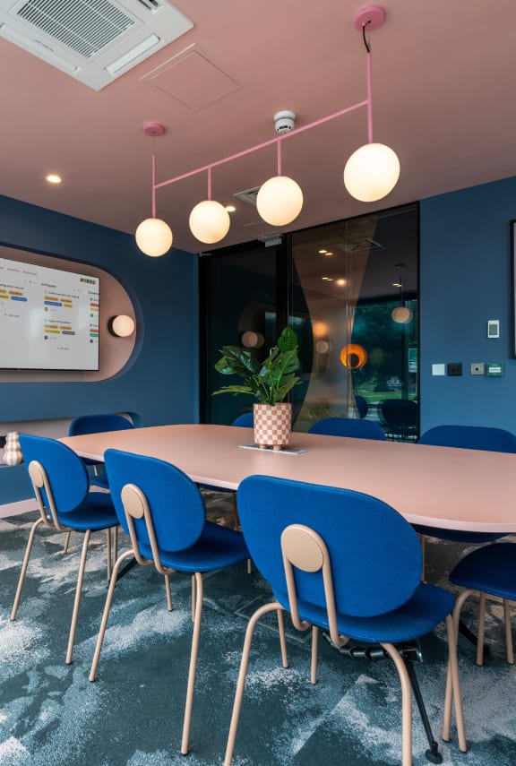 a conference room with a table and chairs and a screen on the wall