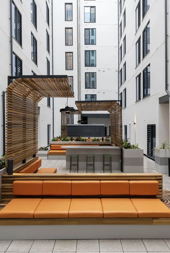 a courtyard with orange benches and a table in front of a building