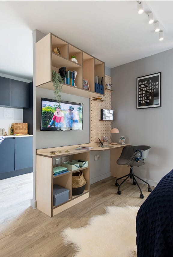 a study area with a desk and a tv in a bedroom
