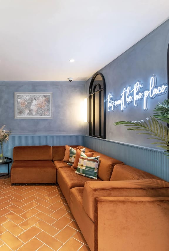 a living room with couches and a neon sign on the wall