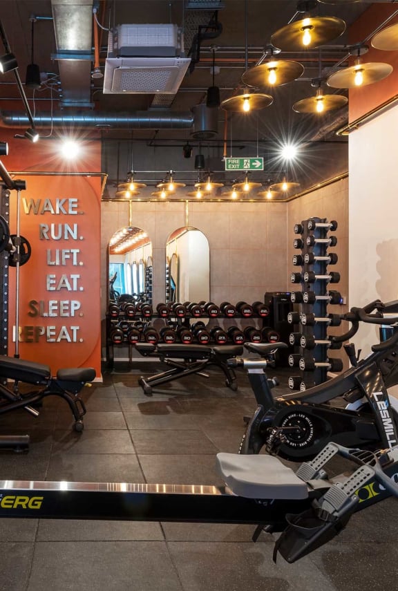 a gym with weights and a sign that reads make run lift eat sleep beat