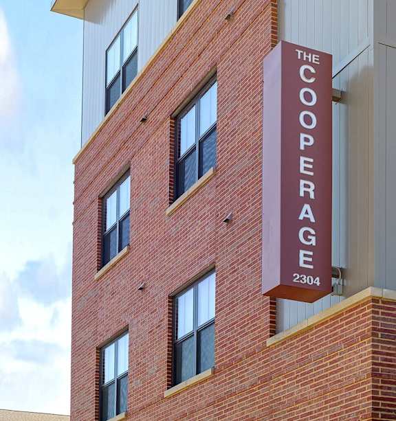 A tall brick building with a sign that says "The Cooperage" on it.
