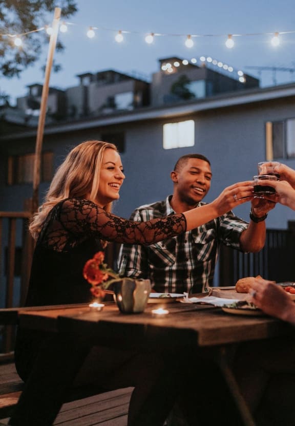 Man and Woman Sitting at Table Holding Drinks and Smiling