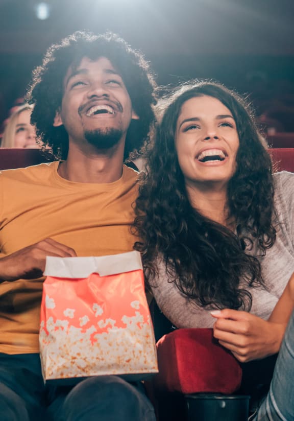 a man and a woman laughing while watching a movie at a movie theater