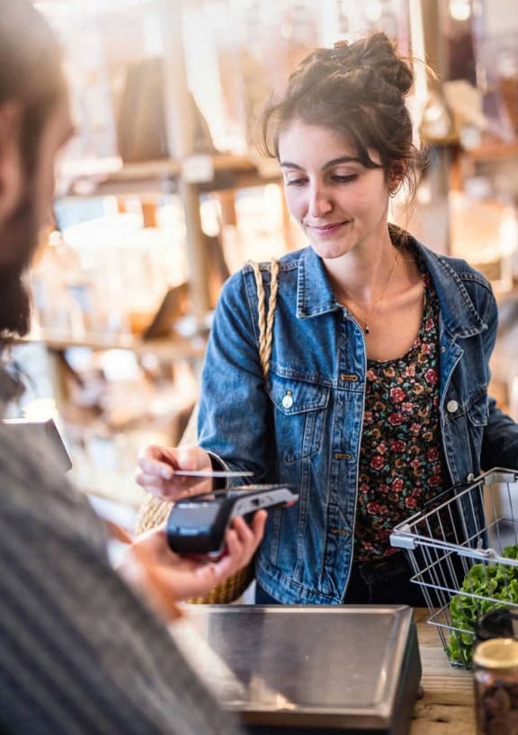 a woman standing at a counter paying with credit card