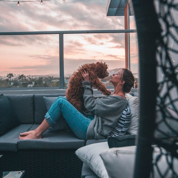 a woman and her dog sitting on a couch looking out of a window