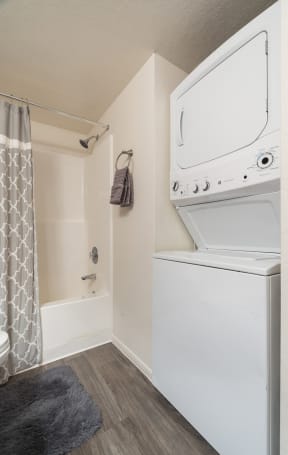 a white washer and dryer in a bathroom with a shower