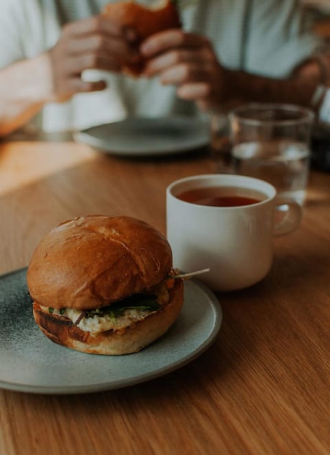 a sandwich on a plate next to a cup of coffee