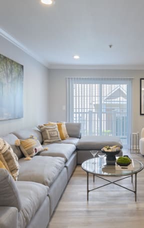 a living room with a large couch and a coffee table with a bowl of fruit on it