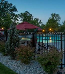 A pool surrounded by a black fence and a small building with a red roof.