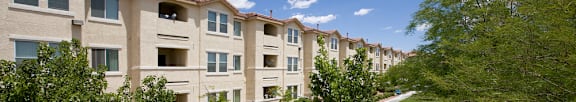 Apartment complex with a green lawn and trees.
