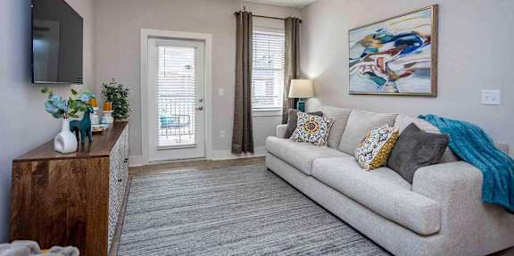 A living room with a couch, a wooden cabinet, a television, and a painting on the wall.