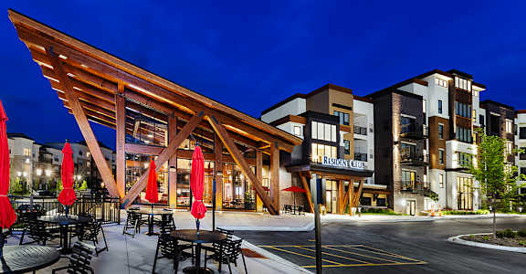 A residential club with a wooden roof and tables and chairs set up outside.
