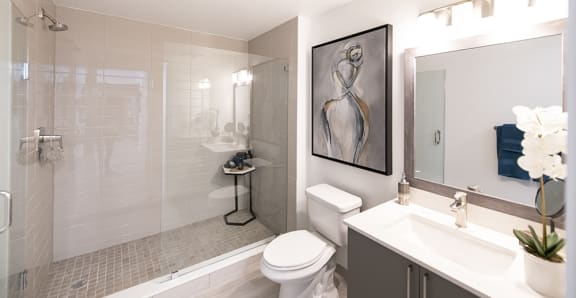 a bathroom with a white sink and toilet and a shower with a glass door