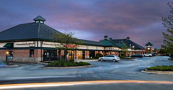 A Starbucks coffee shop is shown with cars parked in front.