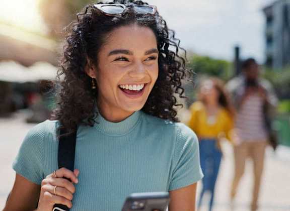a woman smiling while looking at her cell phone